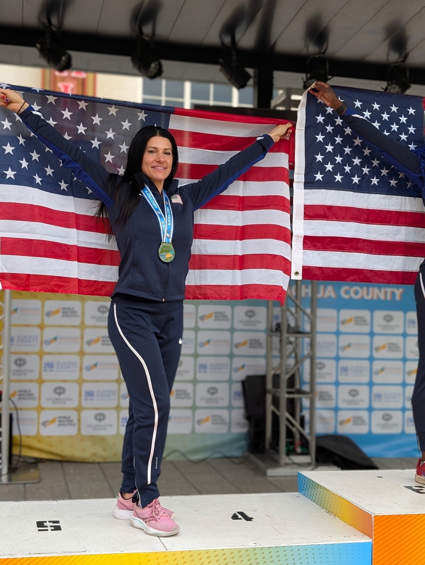 Amanda O’Connor smiling with a medal and holding the United States flag